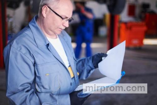 Инспектор технадзора с папкой документов проверяет маркировку силового оборудования