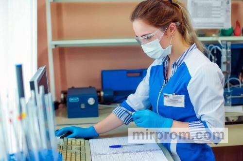 Инспектор в белом халате изучает журналы отклонений в чистой зоне лаборатории