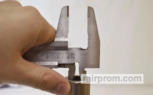 Процесс замера хвостовика нестандартного фитинга штангенциркулем на производстве